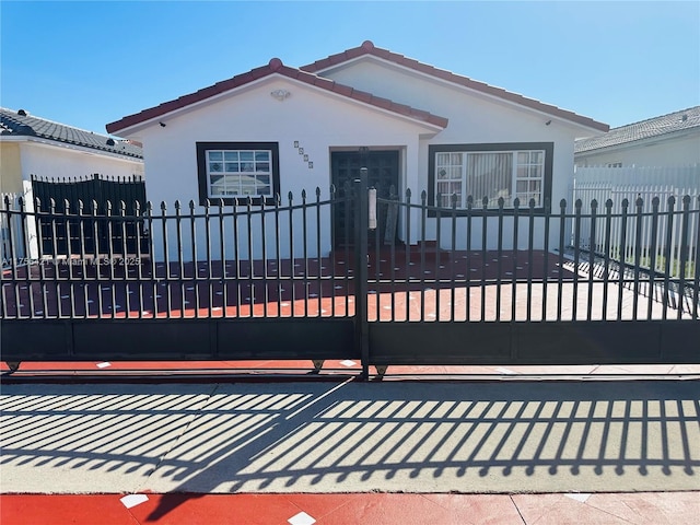 view of front of house featuring a gate, stucco siding, a tiled roof, and a fenced front yard