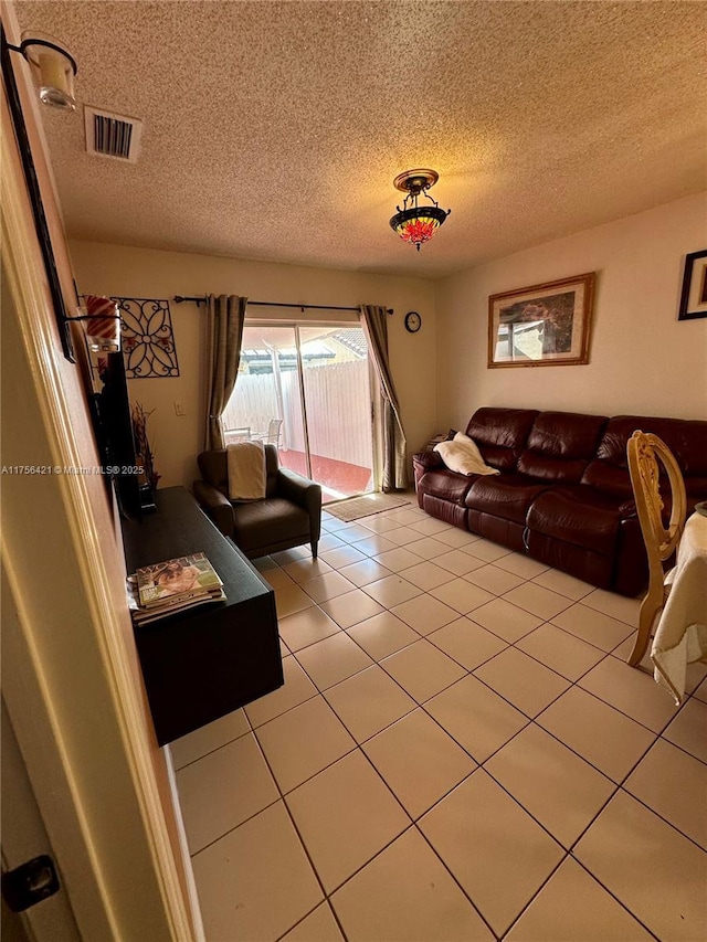 living room featuring a textured ceiling, visible vents, and light tile patterned floors
