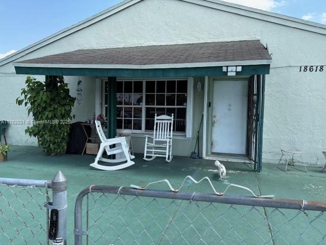 back of house with stucco siding, a patio, and roof with shingles