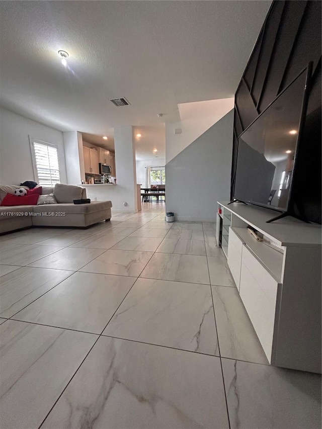 living room featuring visible vents, marble finish floor, and a textured ceiling