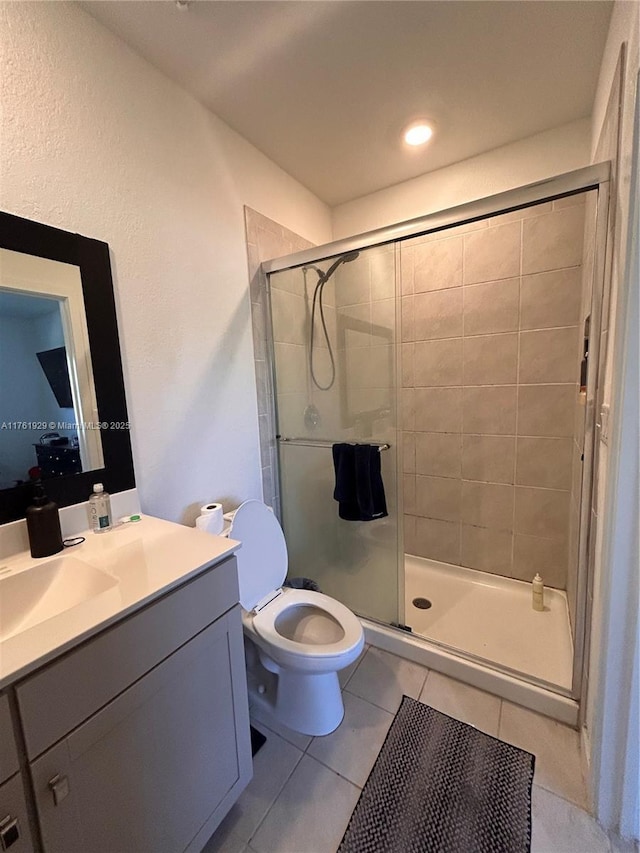 bathroom featuring vanity, toilet, a stall shower, and tile patterned flooring