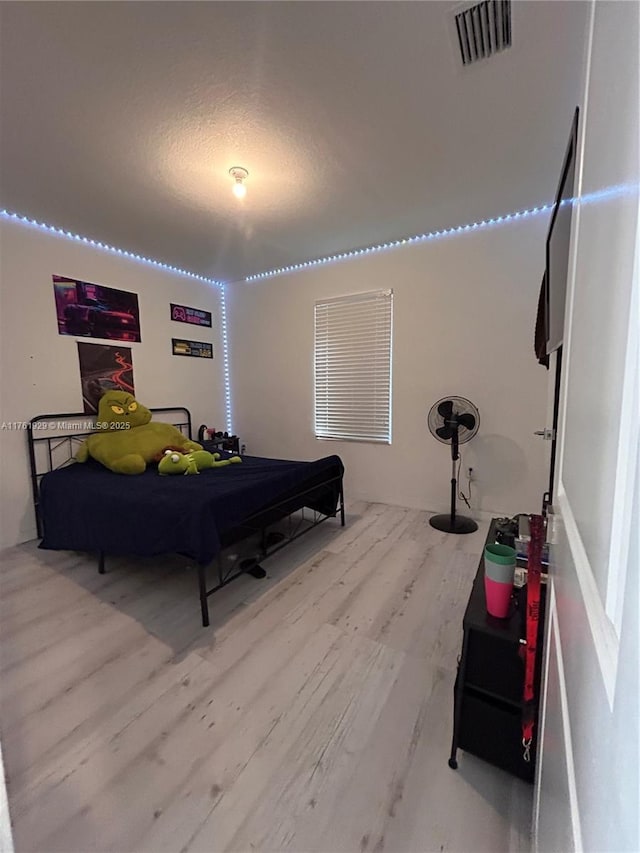 bedroom featuring wood finished floors, visible vents, and a textured ceiling