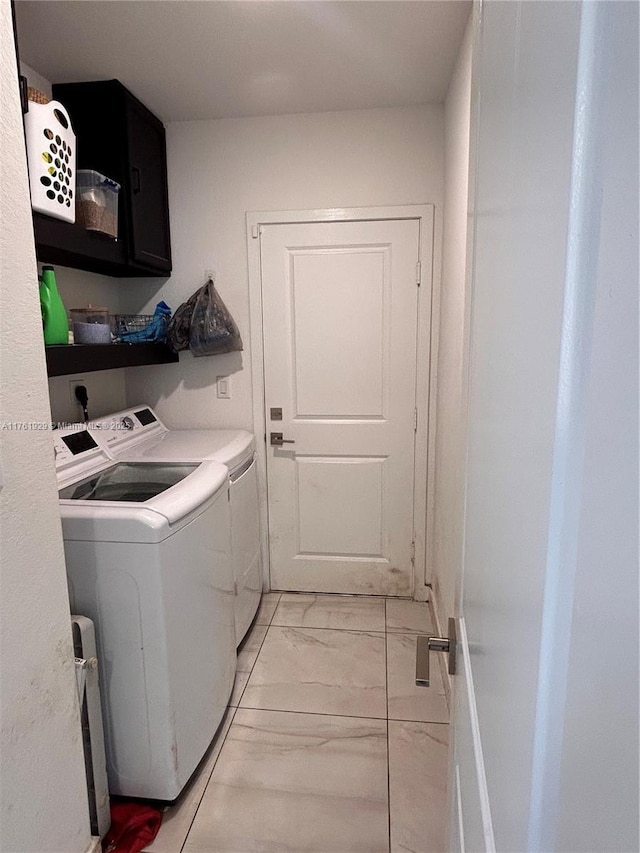 clothes washing area featuring cabinet space, washing machine and dryer, and marble finish floor