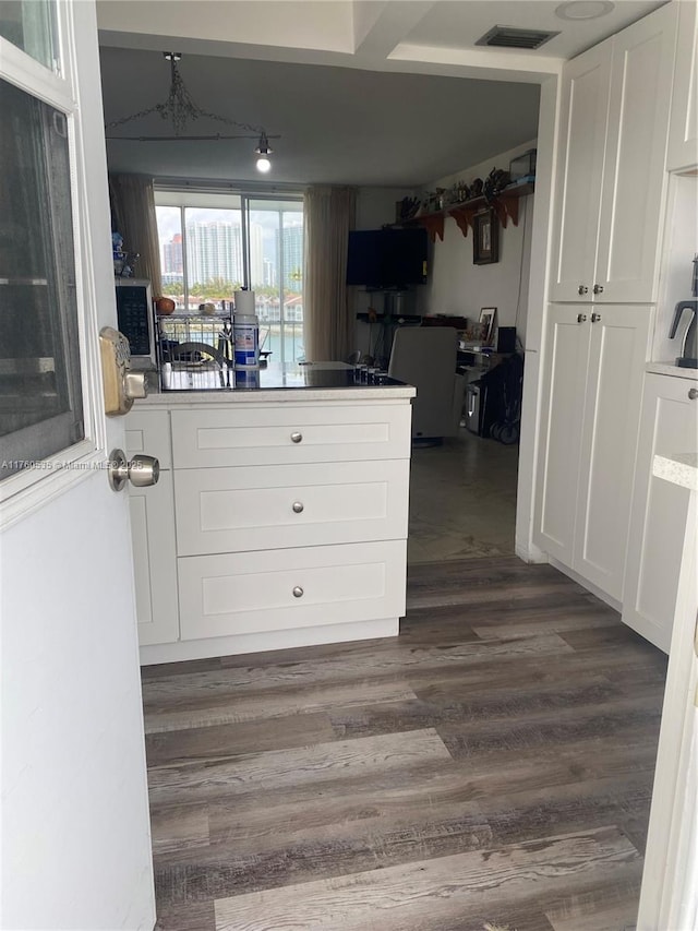 interior space featuring dark wood finished floors, a peninsula, white cabinets, and visible vents