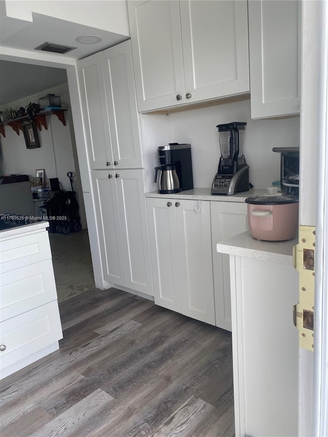 kitchen featuring visible vents, wood finished floors, light countertops, and white cabinetry