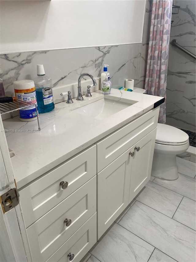 full bathroom featuring toilet, marble finish floor, a stall shower, tile walls, and vanity