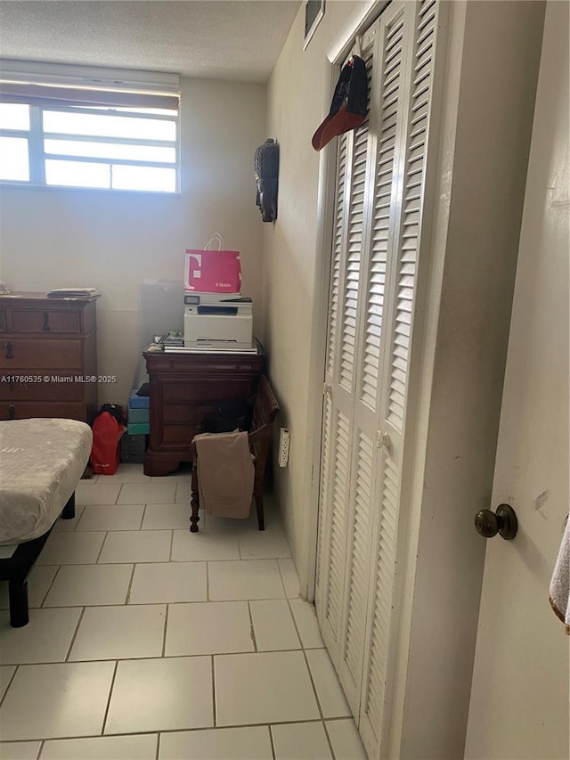 bedroom featuring light tile patterned floors, visible vents, and a closet