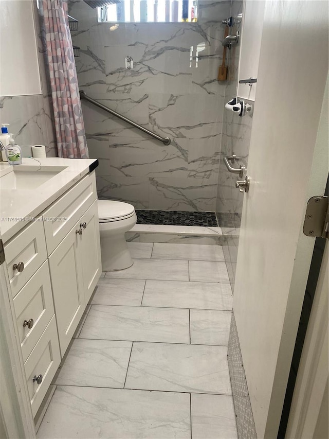 bathroom with vanity, toilet, marble finish floor, and a marble finish shower