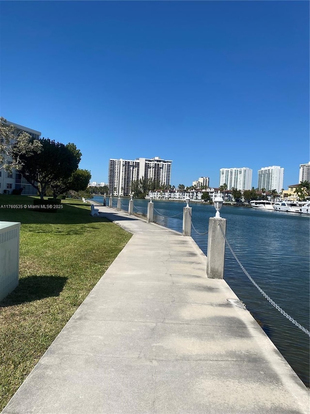 view of dock featuring a lawn, a view of city, and a water view