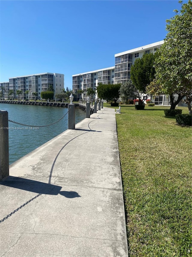 view of property's community with a water view and a lawn