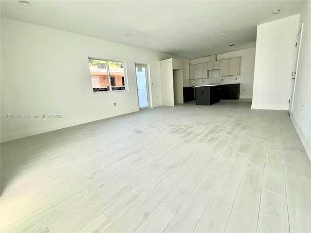 unfurnished living room with baseboards and light wood-style floors
