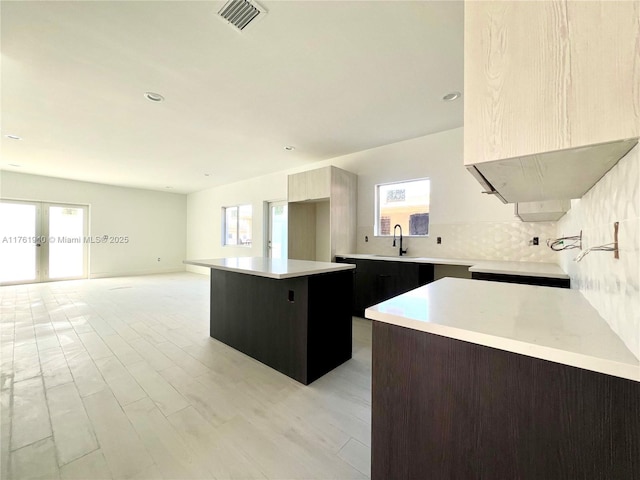 kitchen with light countertops, a kitchen island, a wealth of natural light, visible vents, and modern cabinets