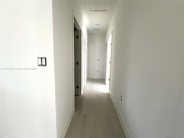 hall featuring baseboards and light wood-type flooring