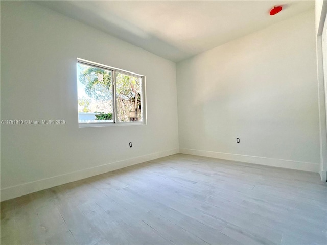 spare room featuring light wood finished floors and baseboards