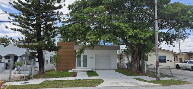 view of front of house with french doors, concrete driveway, stucco siding, and fence