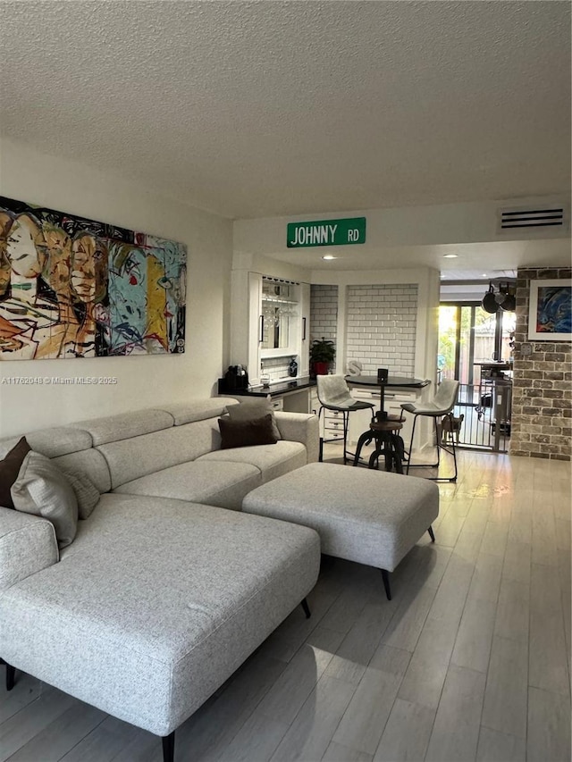 living room featuring visible vents, a textured ceiling, and wood finished floors