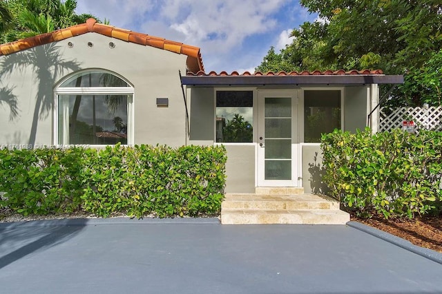 entrance to property with stucco siding and a tile roof