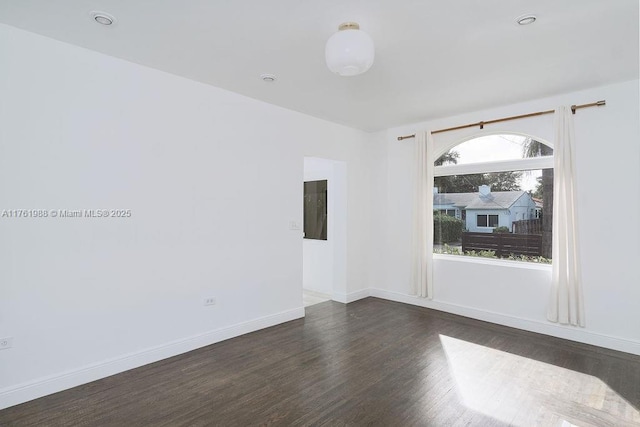 unfurnished room featuring dark wood-style floors and baseboards