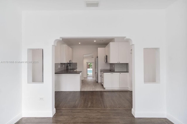 kitchen featuring wood finished floors, visible vents, stainless steel range, white cabinets, and dark countertops