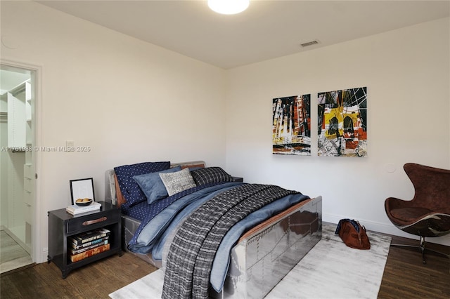 bedroom with visible vents, baseboards, and wood finished floors