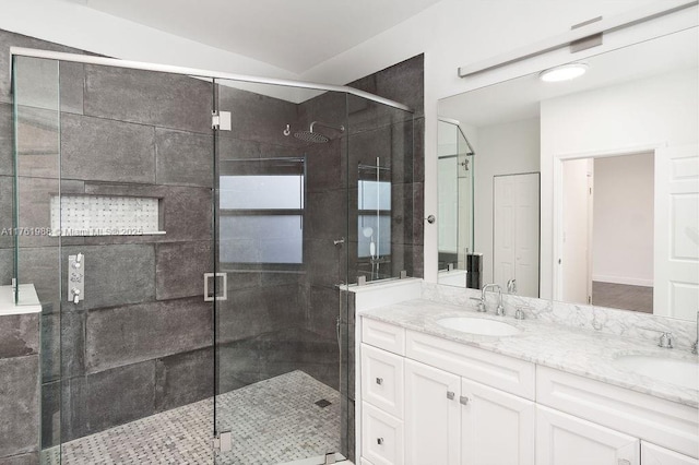 bathroom with a sink, a stall shower, and double vanity