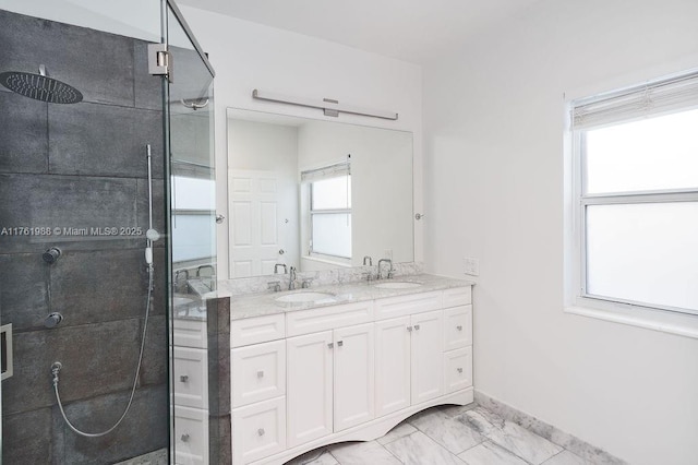 full bathroom featuring marble finish floor, a tile shower, and a sink