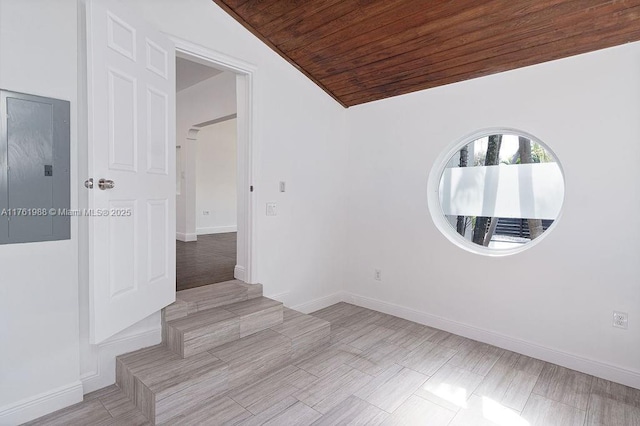 empty room featuring electric panel, baseboards, lofted ceiling, and wooden ceiling