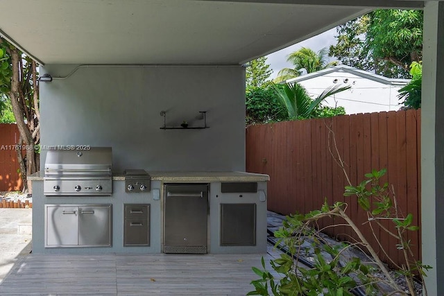 view of patio / terrace with grilling area, an outdoor kitchen, a deck, and fence