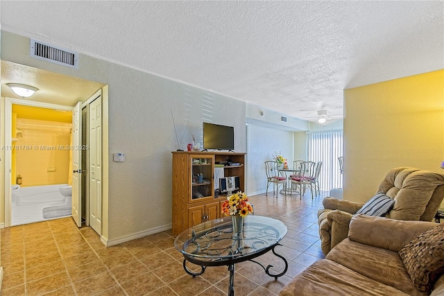 tiled living room with visible vents, a textured ceiling, a ceiling fan, and a textured wall