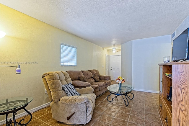 living room with a textured wall, baseboards, a textured ceiling, and dark tile patterned flooring