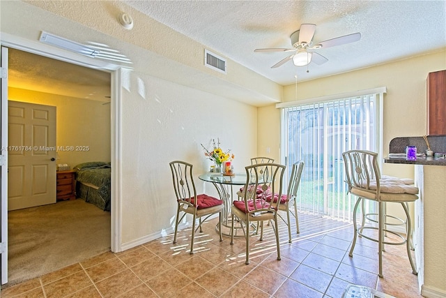 dining room with visible vents, a ceiling fan, a textured ceiling, light tile patterned floors, and baseboards