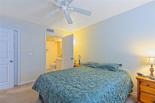 carpeted bedroom featuring baseboards, a ceiling fan, visible vents, and connected bathroom