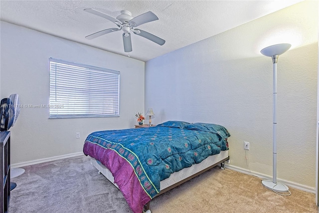 carpeted bedroom with ceiling fan, baseboards, and a textured ceiling