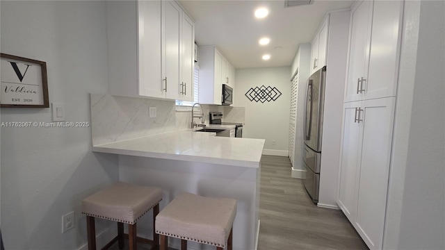 kitchen featuring tasteful backsplash, white cabinets, and appliances with stainless steel finishes