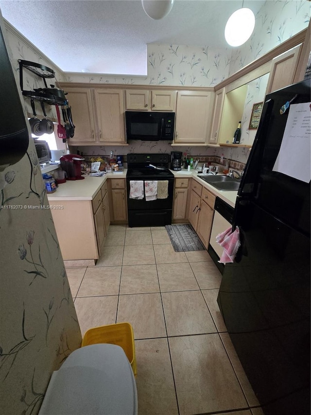 kitchen with light tile patterned floors, wallpapered walls, a sink, black appliances, and light countertops