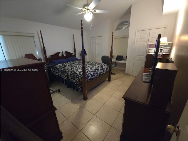 bedroom with lofted ceiling, light tile patterned flooring, two closets, and ceiling fan