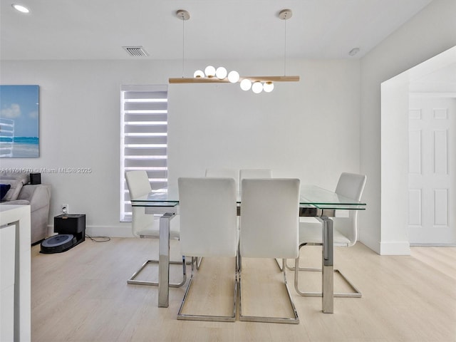 dining space featuring wood finished floors, visible vents, and baseboards