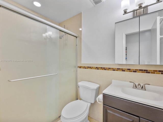 full bath with vanity, visible vents, a stall shower, tile walls, and toilet