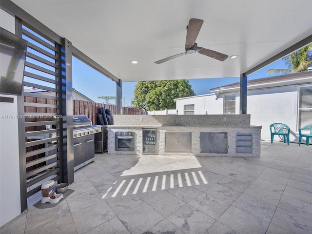 view of patio featuring stairway, a ceiling fan, beverage cooler, fence, and an outdoor kitchen