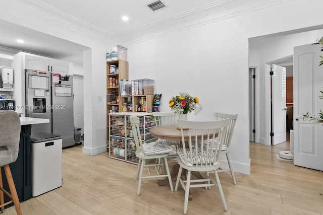 dining room featuring visible vents, baseboards, light wood-type flooring, ornamental molding, and recessed lighting