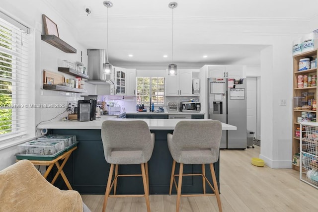 kitchen with crown molding, a peninsula, range hood, and stainless steel appliances