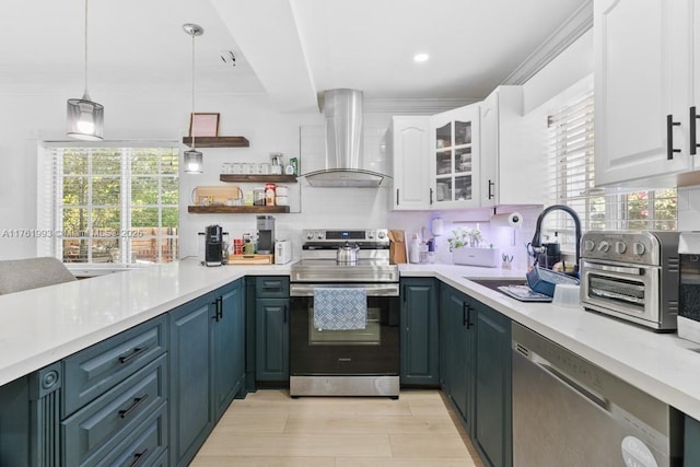 kitchen with a sink, appliances with stainless steel finishes, wall chimney exhaust hood, white cabinets, and decorative backsplash