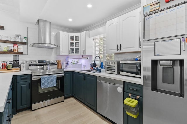 kitchen featuring a sink, backsplash, white cabinetry, appliances with stainless steel finishes, and wall chimney range hood