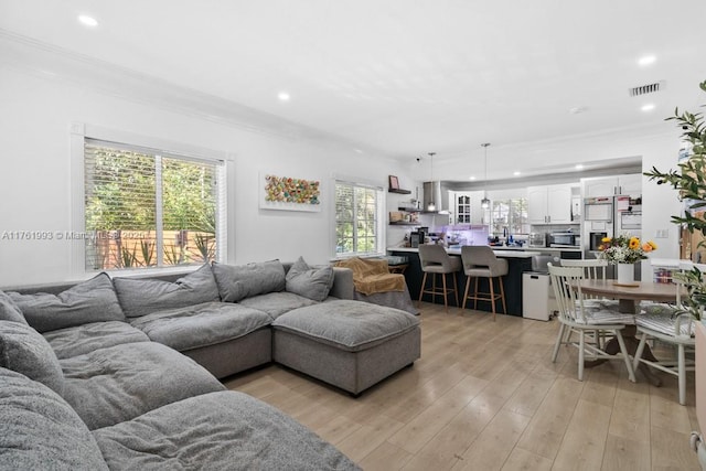 living area featuring light wood-type flooring, visible vents, recessed lighting, and crown molding