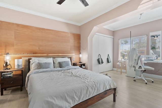 bedroom with baseboards, light wood-type flooring, ornamental molding, a closet, and a ceiling fan