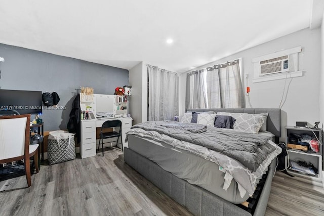 bedroom with an AC wall unit and wood finished floors