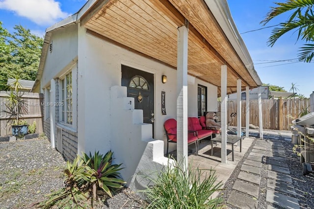 view of side of property featuring a patio, fence, and stucco siding