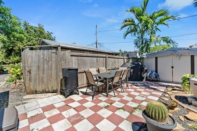 view of patio / terrace with outdoor dining space, fence, a shed, grilling area, and an outdoor structure