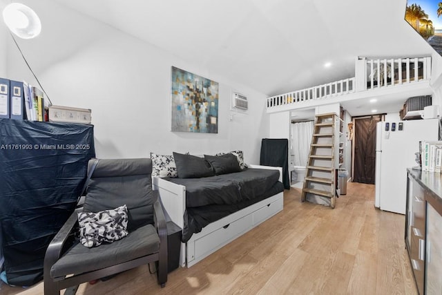 bedroom with freestanding refrigerator, a wall mounted air conditioner, light wood finished floors, and vaulted ceiling