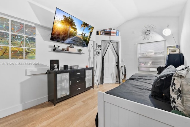 bedroom featuring lofted ceiling, light wood-style floors, and baseboards